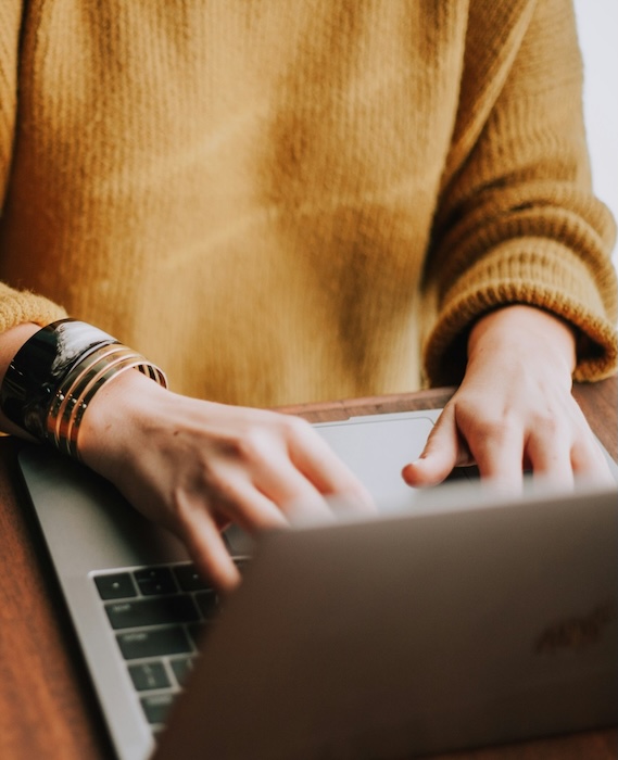 A woman engaged in typing on a laptop, surrounded by a tidy desk environment.